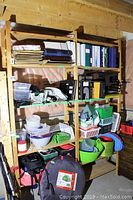 Front full view of the wooden shelving unit filled with various storage items including containers, binders, and bags, showing unit condition and shelving design.