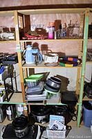 Two shelves showing kitchen items including blue Bodum cafeteria coffee maker, thermos, baking sheets, baskets, glassware, and appliances on bottom shelf not included.