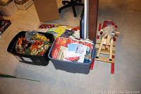 Wide angle showing the wooden rocking horse beside three totes containing gift bags, seasonal faux floral decor, and other gift wrapping materials.
