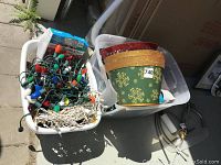 Photo of two bins containing assorted Christmas lights and decorative baskets including Carlton Santa-Lites boxes and strings of colored and white lights.