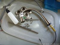 Assortment of faucet parts including gooseneck spout, mounting rings, hoses, and soap dispenser with tag labeled 741.