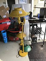 Full view of mustard yellow floor lamp with green metal shade and additional mustard yellow lamp heads in a garage setting.