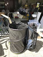 Photo showing the portable black plastic leaf collector on wheels next to the golf bag, highlighting size and portability.