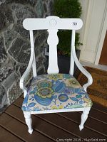 Front view of the white wooden chair showing carved backrest and floral seat upholstery.