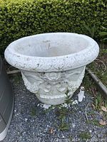 Full view of large round garden urn showing overall shape, texture, and weathering.