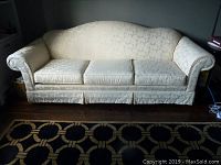 Front view of the cream damask couch showing full length and seating arrangement with three cushions.