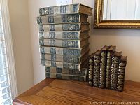 10 vintage World Book encyclopedia volumes stacked horizontally on wooden surface, showing spine details with volume numbers and publication years.