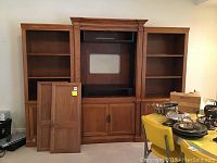Front view of the three-piece oak entertainment center with two detached cabinet doors placed in front.