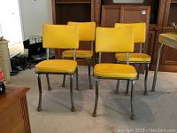 Four vintage chairs arranged on carpeted floor, showing front and side views of yellow vinyl seats and backs with tubular metal frames.