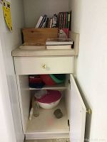 Cookbooks, wooden box and plastic bowls in a kitchen cabinet shelf