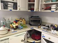 Kitchen counter with Cuisinart toaster oven, ceramic canisters with fruit designs, decorative corked glass, stoneware bowls, and various kitchen utensils