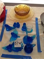 Entire collection laid out, showing blue glass bluebird figurines and amber glass serving plates and bowl