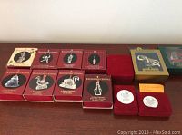 Set of original boxes for Waterford Crystal 12 Days of Christmas ornaments, thirteen in total displayed in red and green boxes on a table.