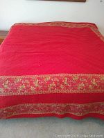 Full view of king size red quilted bedding with floral border edges