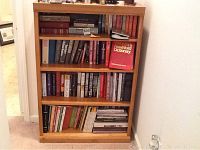 Full frontal image of a wood bookcase filled with books to illustrate size and condition.