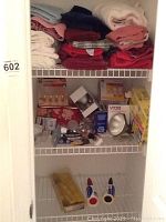 Image showing multiple shelves with towels, light bulbs in boxes, cleaning kit, lint rollers and assorted small items