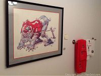 Framed artwork of a UGA football player in red and gray uniform hung on the wall with two UGA embroidered towels on towel racks