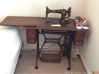 Another front angle of the Singer sewing machine with table and items on top, showing scale and context.