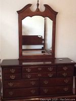 Front view of the dresser with the mirror mounted on top, showing the wood finish and drawer layout.
