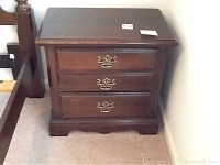 Front view of the wood night stand with three drawers and brass handles