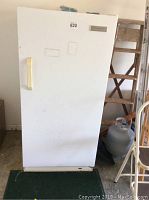 Front view of white upright freezer showing the door with a handle and the overall height and width.