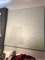 Front view of the large square canvas artwork hung on a wall, showing abstract pastel shapes in light green and white.