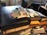 Stack of four black stamp albums with loose envelopes and booklets on top