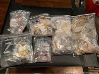 Plastic resealable bags containing multiple pairs of gold and silver plated earrings, some labeled with handwritten text.