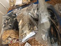 Bagged gold plated heavy chain link belts and other accessories packed in plastic bags on a woven surface