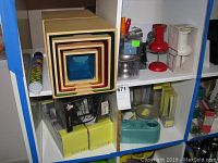 Shelf with wooden nesting cubes, giant push pins, paperweight set, and other small office and decor items.