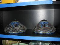 Two stained glass lamp shades on shelf