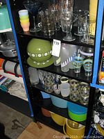 Full view of shelves with vintage glassware, pastel cups, and ice buckets including green and yellow ones