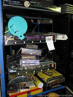 Shelf view showing several boxed games including a Karim Rashid Backgammon Set box, a turquoise Alien clock, and other boxed adult games stacked