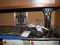 Shelf holding multiple items including stained glass lamp, large quartz crystals, and stained glass wall hangings.