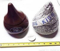 Two large ceramic Hershey's Kisses tins with measuring tape and Hershey's pin to show size