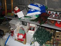 Shelves with assorted Christmas items including stockings, string lights, Santa figurines, boxes, and bags of decorative snow.