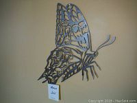 Steel butterfly wall art showing intricate cut-out patterns on wings and body, mounted on a light wall background.