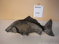 Side view of metal fish sculpture showing textured scales and fins