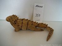 Side view of segmented wooden lizard with burnt-in patterns and detailed facial features