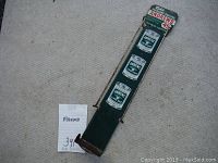 Full view of the metal display rack laid on carpet, showing green base and side arms with painted product graphics.