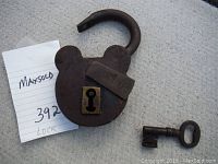 Padlock, key and note on concrete surface from side angle showing open shackle.