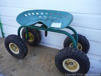 Front-side view of green metal garden seat with perforated swivel seat and four air-filled knobby tires on green tubular frame.