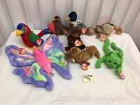 Eight assorted Beanie Babies on white table, each with original Ty tag visible