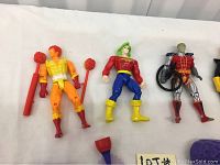 Close view of Marvel figures showing orange and yellow clad figure, colorful figure in blue pants and red shirt, and silver armored figure with wheelchair.