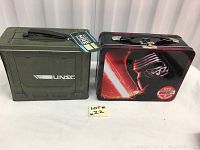 Two tin lunch boxes side by side. Left is olive green Halo UNSC box. Right is black Star Wars Kylo Ren box.