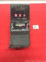 Open view of the makeup set showing nail polishes, eyeshadow palette and cosmetic items inside the black polka dot case.