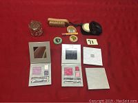 Overview of makeup lot with eyeshadow palettes, grooming brushes, and small containers.