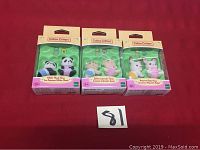 Three Calico Critters twin sets in original packaging on a red background
