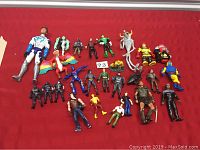 Photo showing approximately 27 assorted action figures including Batman and other superheroes, fantasy characters, and figures in various costumes, numbered lot tag visible