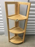 Full front view of foldable wooden corner display shelves with three triangular shelves and supporting frame.